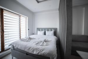 um quarto com uma cama com lençóis brancos e uma janela em NLux 10 Apartment em Kopaonik