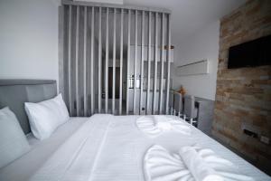 uma cama com lençóis brancos e almofadas num quarto em NLux 10 Apartment em Kopaonik