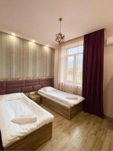 1 dormitorio con 2 camas y ventana en Glendale Boutique Hotel, en Ereván
