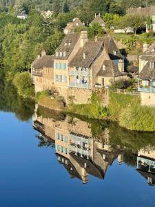 um reflexo de uma casa num corpo de água em Maison en pierre sur les Quais de la Dordogne em Argentat