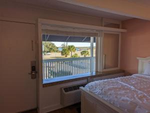 a bedroom with a bed and a window with a balcony at Waterway Condo at Wrightsville! in Wilmington