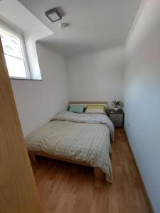 a bed in a white room with a window at chambre très confortable et acclimatée in Audun-le-Tiche