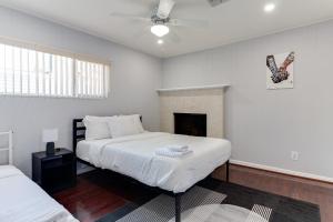 a white bedroom with two beds and a fireplace at 5 Bedroom Charmer with Pool in Reseda +27 photos