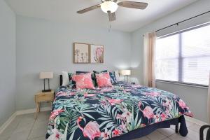 a bedroom with a bed with a floral bedspread and a window at Fun, Resort-style Coastal Villa W Splash Pad! in Sarasota