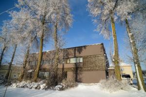 Un bâtiment dans la neige à côté de quelques arbres dans l'établissement Jundula, à Šakiai