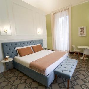 - une chambre avec un grand lit, une table et des chaises dans l'établissement Toscano Palace Luxury Rooms Catania, à Catane