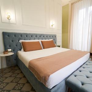 a bedroom with a large bed with a blue headboard at Toscano Palace Luxury Rooms Catania in Catania