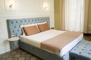 a bedroom with a large bed with a blue headboard at Toscano Palace Luxury Rooms Catania in Catania