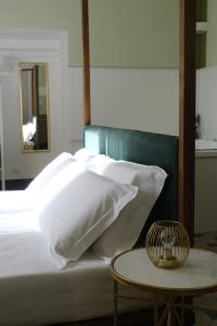 a bed with white pillows and a table with a mirror at Toscano Palace Luxury Rooms Catania in Catania