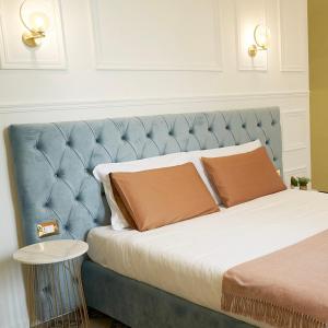 a bed with a blue head board with two pillows at Toscano Palace Luxury Rooms Catania in Catania