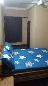a bed with a blue comforter with white stars on it at STUDIO 2 Climatisé et Ventilateur Plafonnier et WIFI GRATUIT A 12 NUITEES DE RESERVATION in Lomé