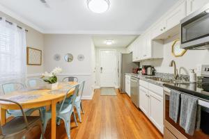 ダーラムにある*Lux Modern Townhome * Downtown* King Beds * Duke*のテーブルと椅子のあるキッチンと白いキャビネットのあるキッチン