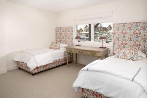 Un dormitorio con dos camas y un escritorio y una ventana. en Spanish Peaks - Highlands Cabin 19, en Big Sky