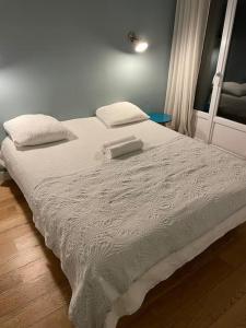 Una cama blanca con dos almohadas encima. en Appartement Roland-Gaross/Boulogne-Billancourt, en Boulogne-Billancourt