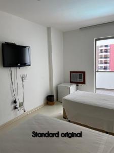a bedroom with two beds and a flat screen tv at Sian Apart Hotel Garvey in Brasília