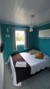 Un dormitorio con una cama con paredes azules y una ventana en Pousada Arpoador de Búzios, en Búzios