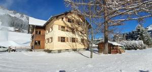 a large building in the snow with a tree at Ferienwohnung Zunzer in Mittelberg