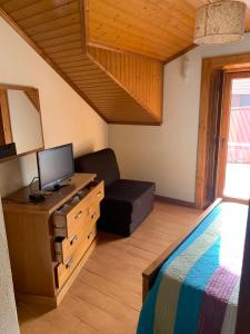 um quarto com uma cama, uma televisão e uma cadeira em Recantos da Estrela em Sabugueiro