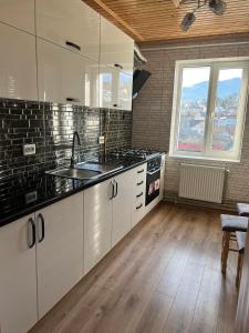 eine Küche mit weißen Schränken und schwarzen Arbeitsplatten in der Unterkunft Carpathian Comfort in Jaremtsche