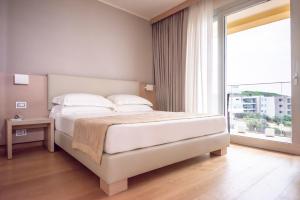 a bedroom with a bed and a large window at Hotel Calabona in Alghero