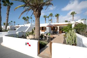 een wit huis met palmbomen ervoor bij Puerto Chico U in Playa Blanca