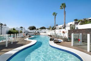 een zwembad in een resort met palmbomen en gebouwen bij Puerto Chico U in Playa Blanca