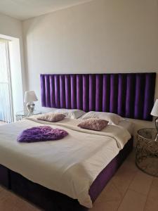 - une chambre avec un grand lit et une tête de lit violette dans l'établissement Serenity 3BR Palm view in Marina, à Dubaï