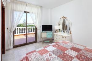 1 dormitorio con cama, TV y balcón en Villa Jacaranda en Chilches