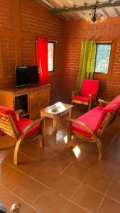 sala de estar con 2 sillas, mesa y TV en Casa de la Luna, Juayúa., en Juayúa