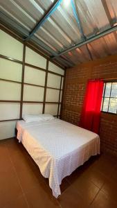 1 dormitorio con 1 cama con cortina roja en Casa de la Luna, Juayúa., en Juayúa