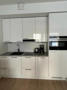 a white kitchen with white cabinets and a sink at City apartment nearby Airport in Vantaa