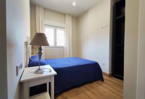 sypialnia z niebieskim łóżkiem i oknem w obiekcie APARTAMENTOS SANLUCAR CASA C w mieście Sanlúcar de Barrameda