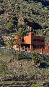 een gebouw met palmbomen voor een berg bij Casa Moni Ferienwohnung mit Meerblick in Playa de Santiago