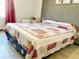 Una cama con edredón en una habitación en Berenice III Apartamentos en Villa Carlos Paz