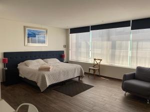 1 dormitorio con 1 cama, 1 silla y 1 sofá en Napoles Suites, en Ciudad de México