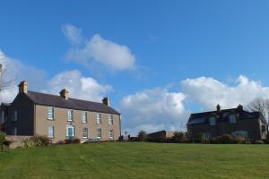 a large brick house on a grassy field at Barnwell Farm Cottages Corn cottage in Greyabbey