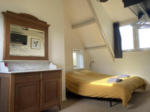 een slaapkamer met een bed, een dressoir en een spiegel bij Landhuis 'De Ontspanning' in Axel