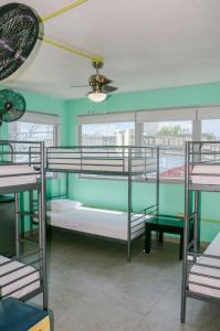 Habitación con 3 literas y ventilador de techo. en Conturce Hostel, en San Juan