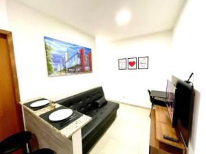 - un salon avec un canapé noir et une télévision dans l'établissement Expo Center - Apartamento Vila Maria - São Paulo, à São Paulo