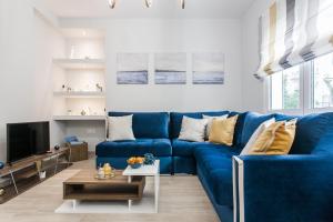 un salon avec un canapé bleu et une télévision dans l'établissement Luxury seaside apartment in Flisvos Palaio Faliro, à Athènes