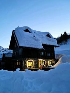 une maison recouverte de neige avec des lumières allumées dans l'établissement Zoncolan Laugiane, à Sutrio