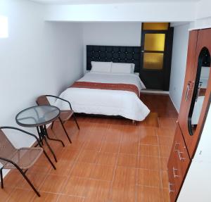 um quarto com uma cama, uma mesa e cadeiras em Cusco de mis Sueños Hostal - II em Cusco