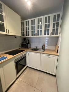 a white kitchen with white cabinets and a sink at Studio close from train station and shops in Luxembourg