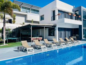 a swimming pool with chairs and a house at Casa Flamboyant With Sea Views & Heated Pool in Adeje