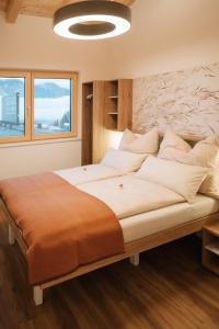 ein großes Bett in einem Zimmer mit einem großen Fenster in der Unterkunft Die Wiesen Apartments in Innsbruck