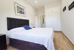 - une chambre avec un grand lit blanc et une tête de lit noire dans l'établissement APARTAMENTOS SANLUCAR CASA D, à Sanlúcar de Barrameda