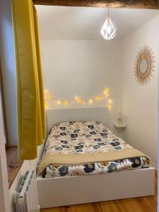 um pequeno quarto com uma cama com uma cortina amarela em Le petit cocon Nîmois em Nîmes