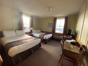 a hotel room with two beds and a desk at Hotel Bedford in Goderich