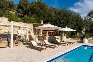 a swimming pool with lounge chairs and umbrellas next to a swimming pool at Loggos View House in Mastorátika