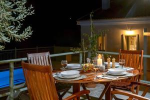 Mastorátika的住宿－Loggos View House，一张木桌,配有椅子和盘子,酒杯